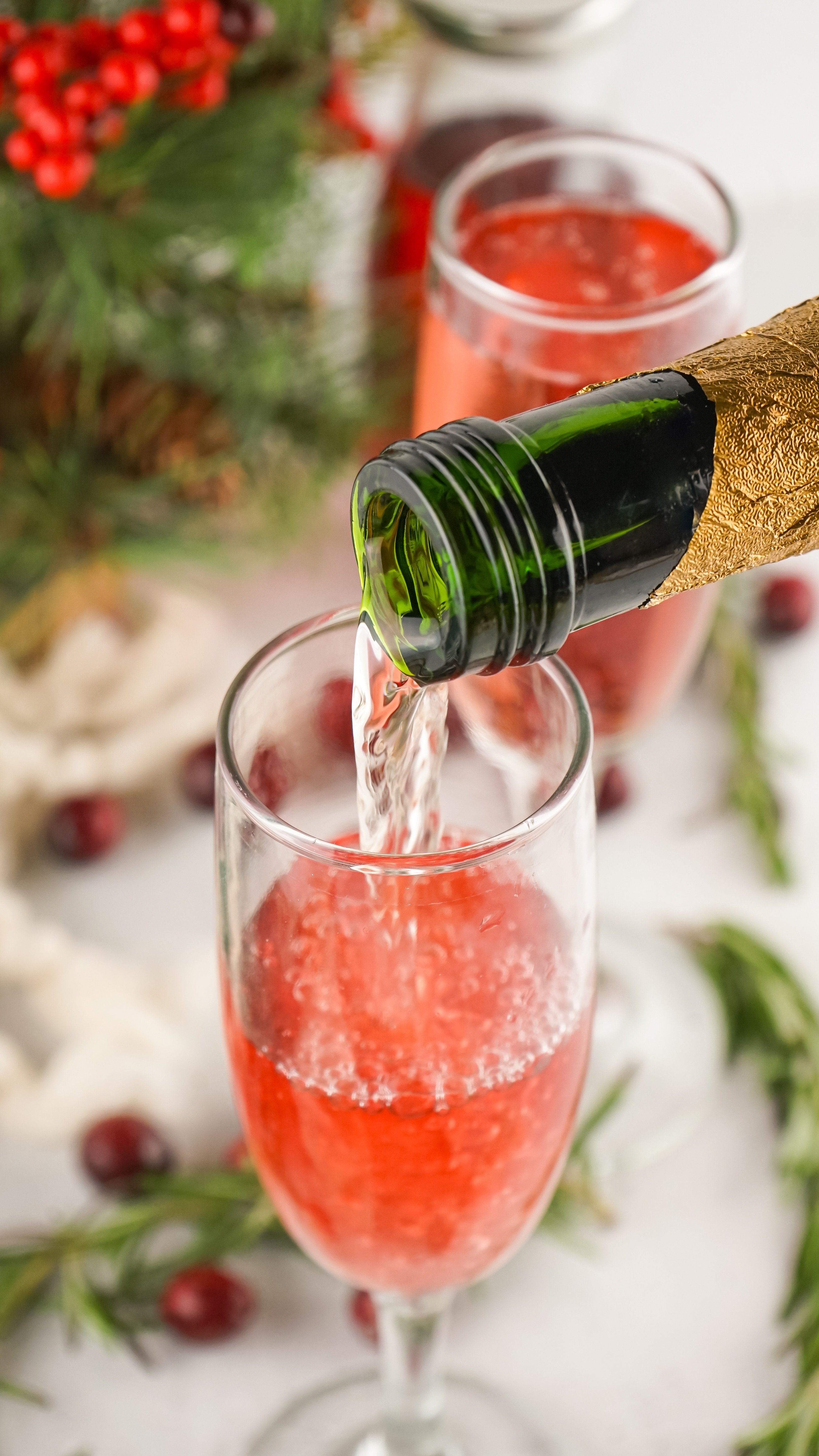 champagne being poured into glass with cranberry juice 