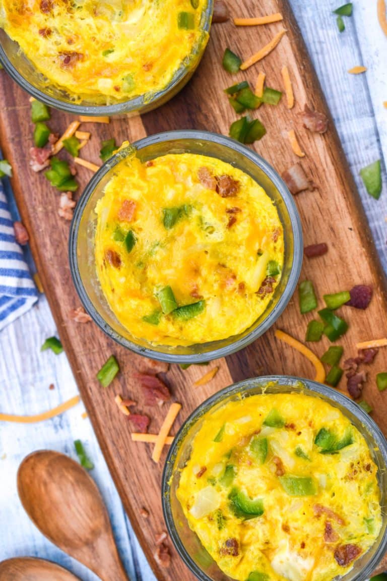 homemade microwave egg scramble cups in small glass bowls on a wooden cutting board