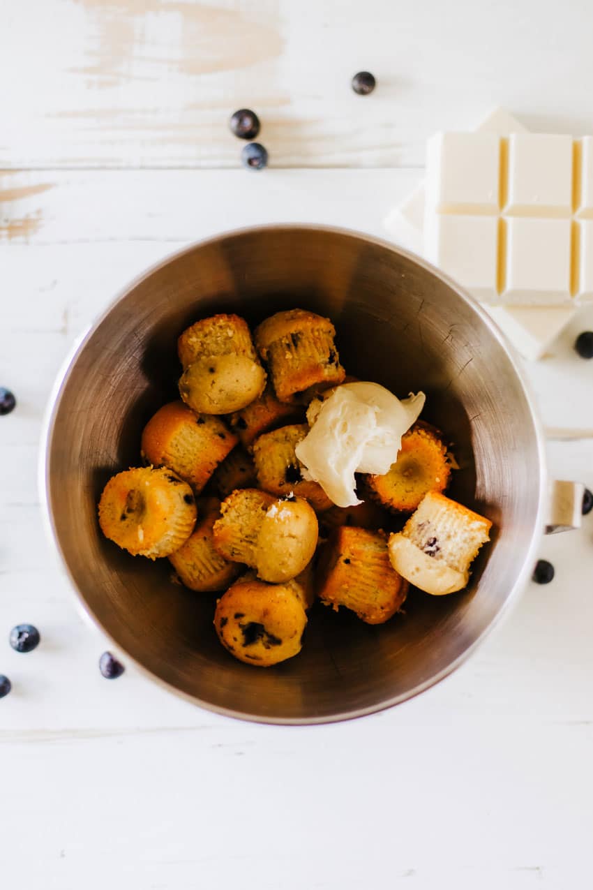 unwrapped mini blueberry muffins and cream cheese in a metal mixing bowl