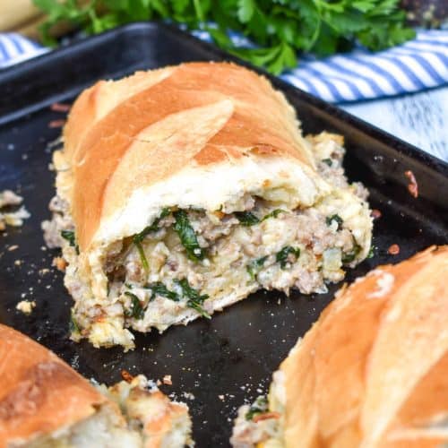 a slice of sausage stuffed french bread sandwich stacked together on a metal baking sheet pan