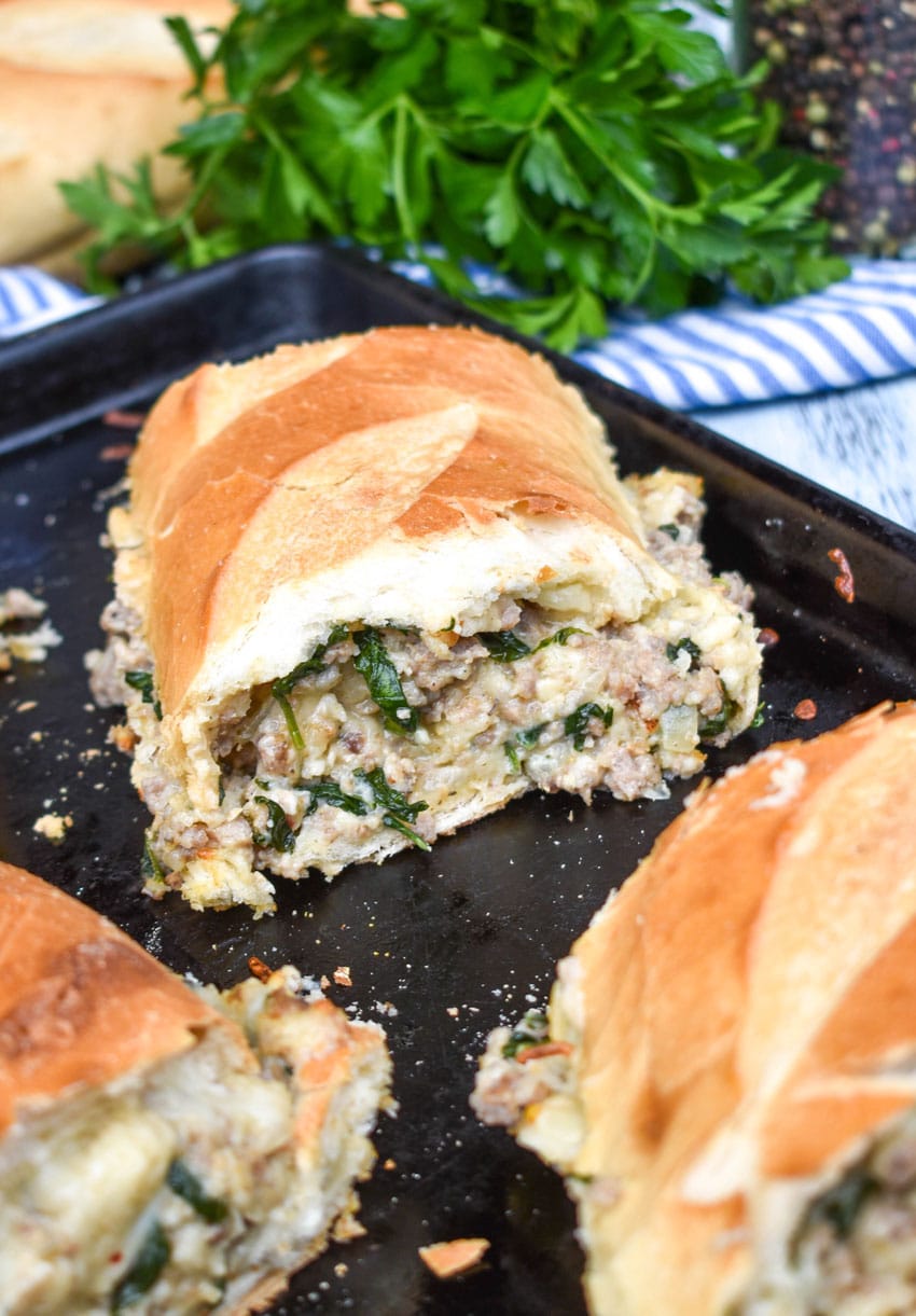 a slice of sausage stuffed french bread sandwich stacked together on a metal baking sheet pan