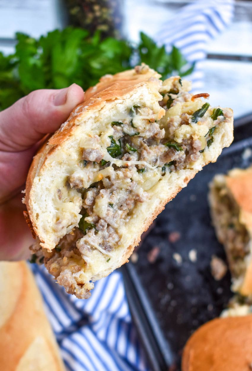 a hand holding up a slice of sausage stuffed french bread