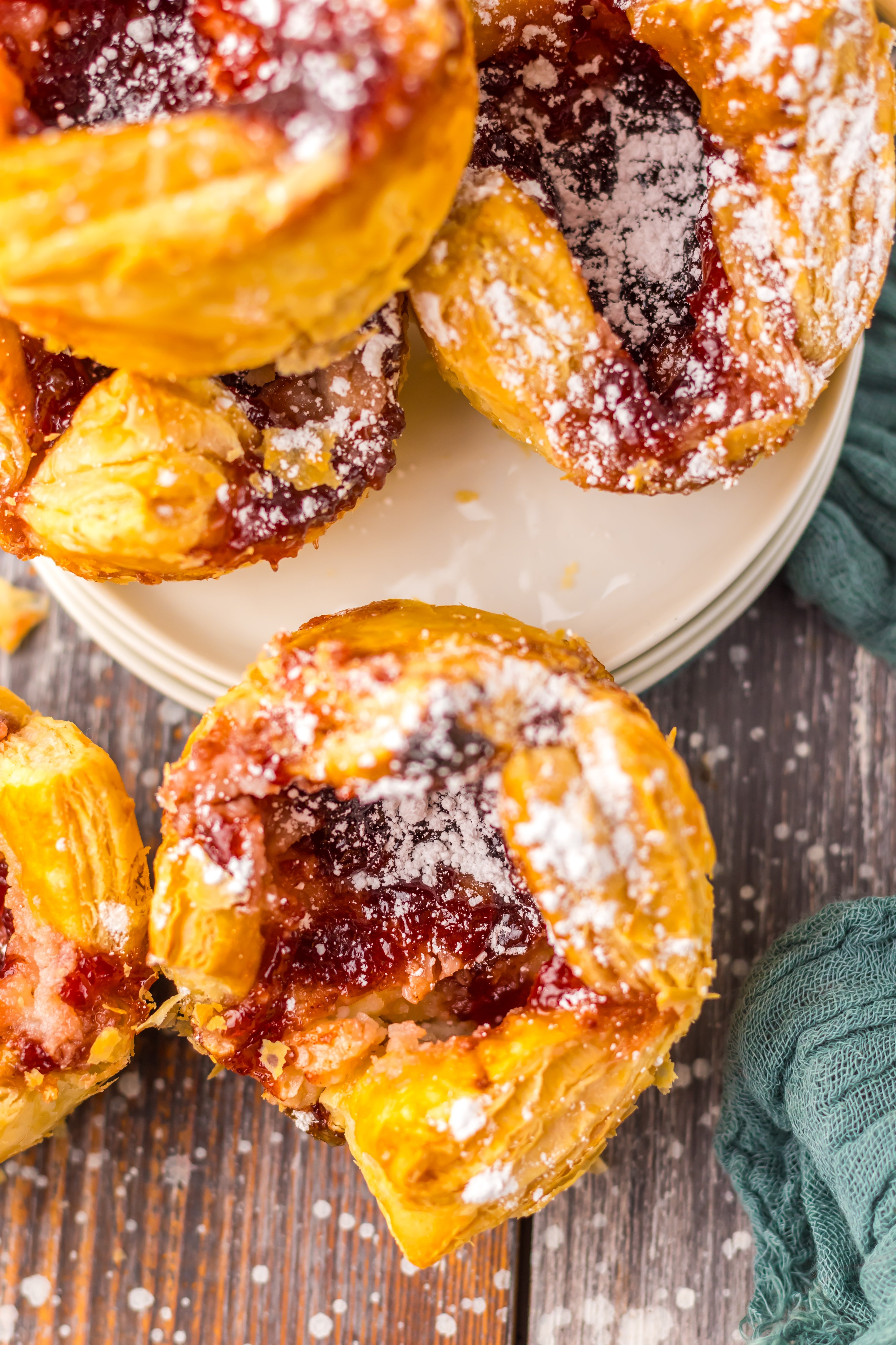 powdered sugar sprinkled sugar plum danishes on a wooden table