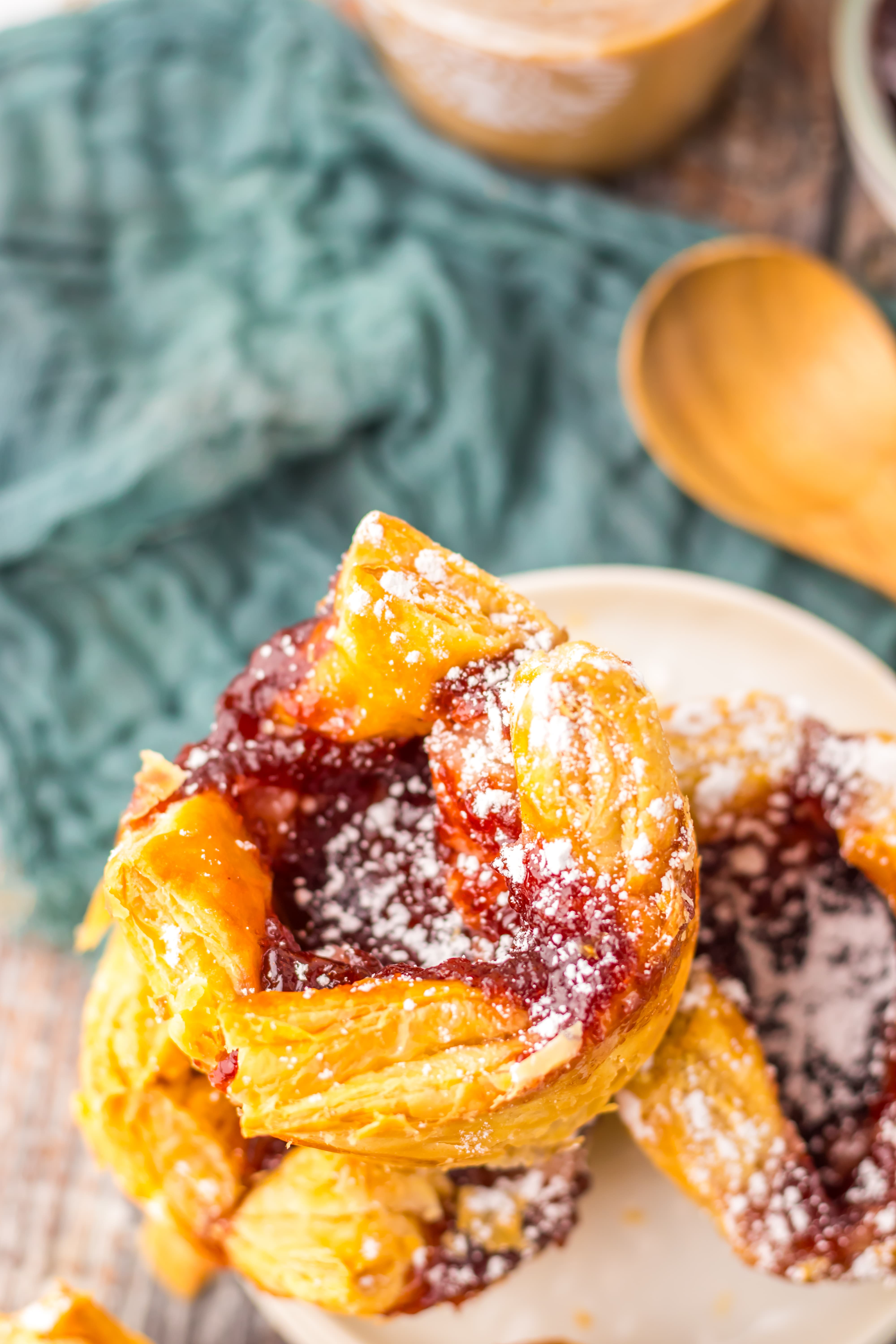 powdered sugar sprinkled sugar plum danishes on a wooden table