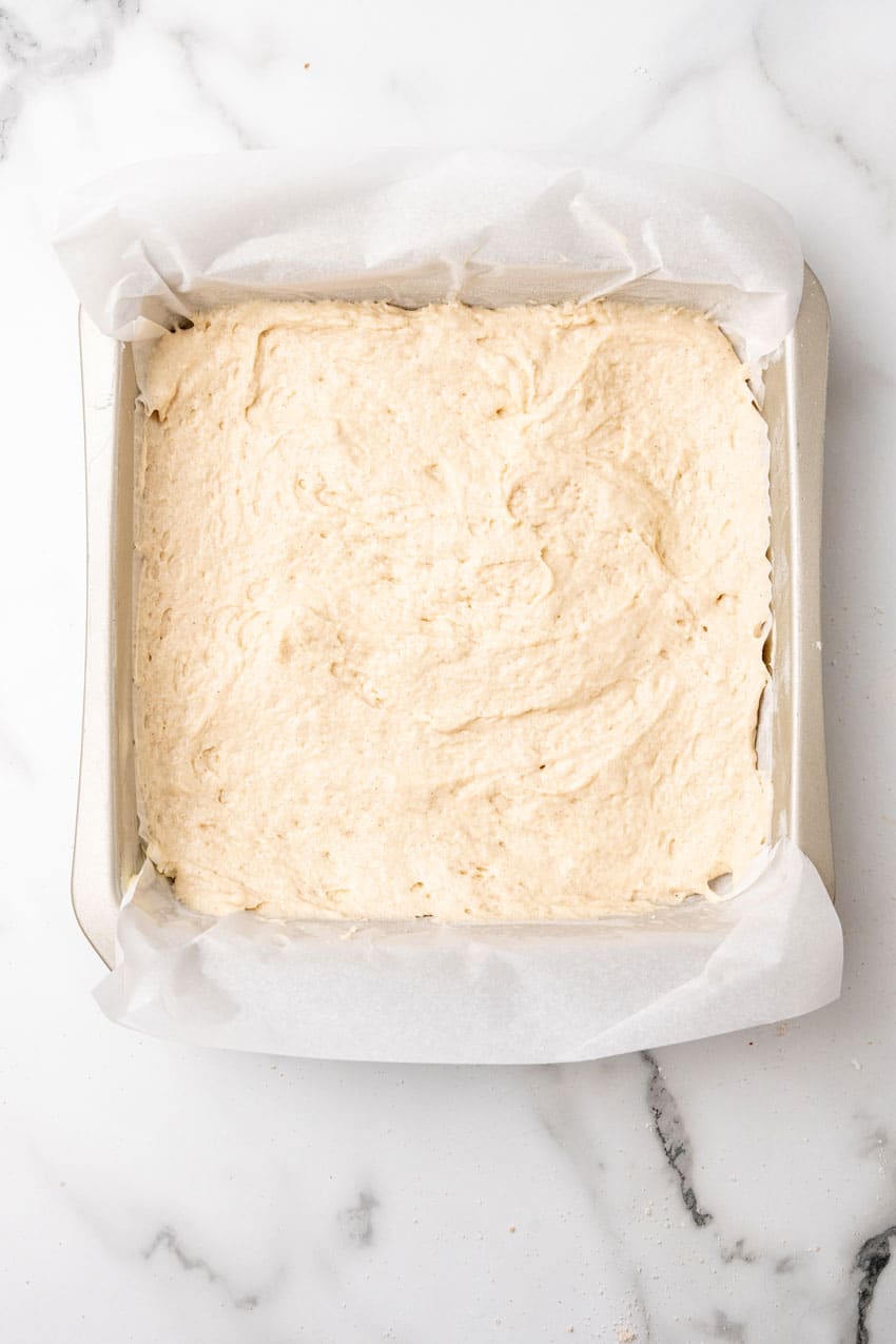 homemade coffee cake batter in a parchment paper lined square baking dish