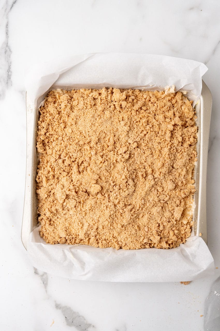 an unbaked bisquick coffee cake in a parchment paper lined square baking dish