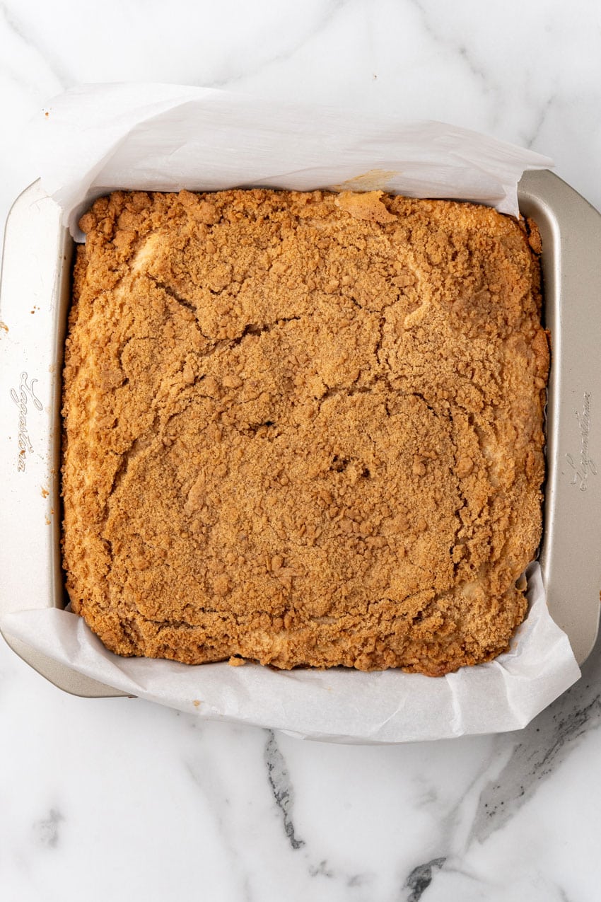 a baked bisquick coffee cake in a parchment paper lined square baking dish