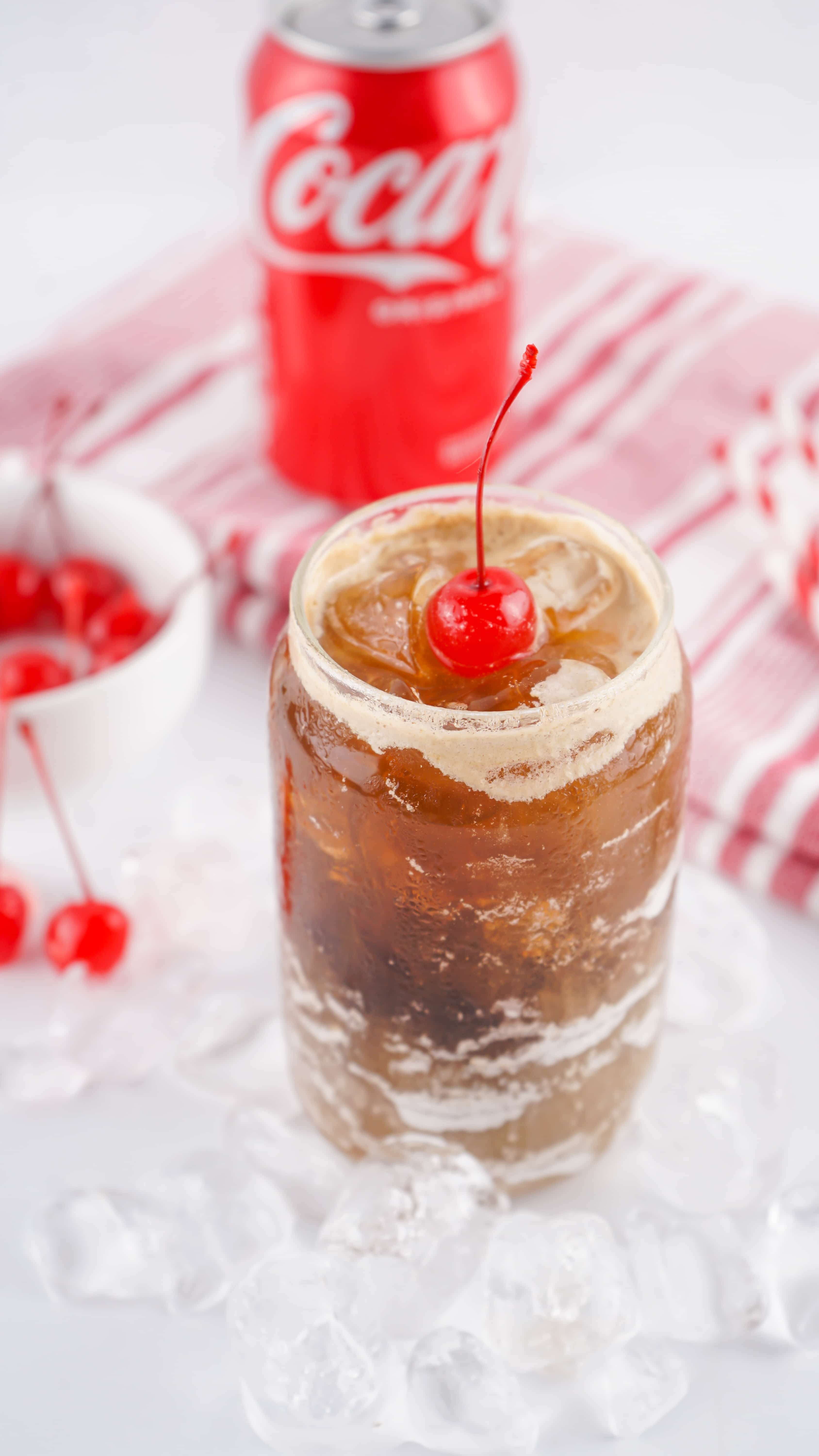 fluffy coke in a glass jar topped with a maraschino cherry