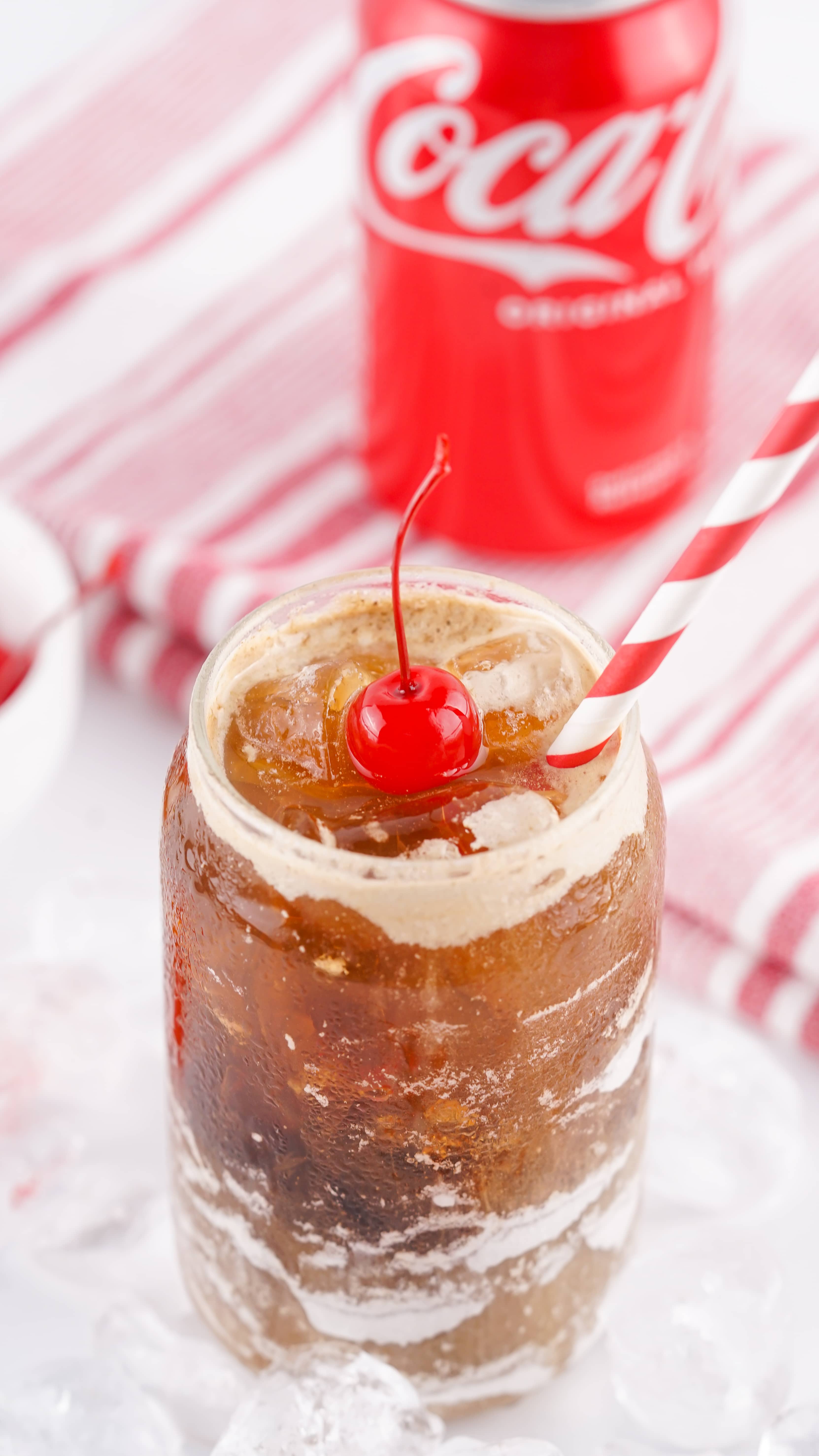 fluffy coke in a glass jar topped with a maraschino cherry