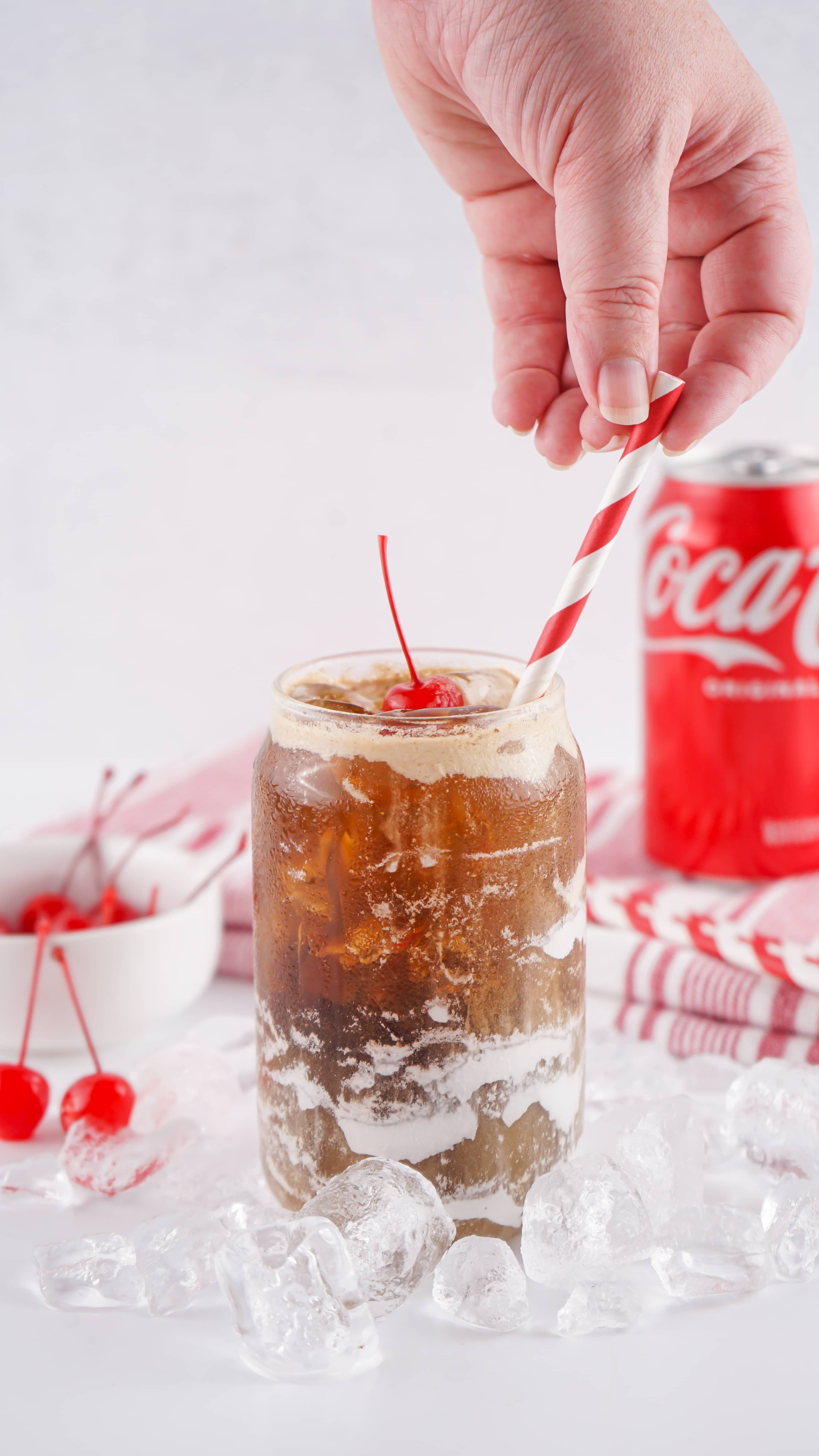 fluffy coke in a glass jar topped with a maraschino cherry