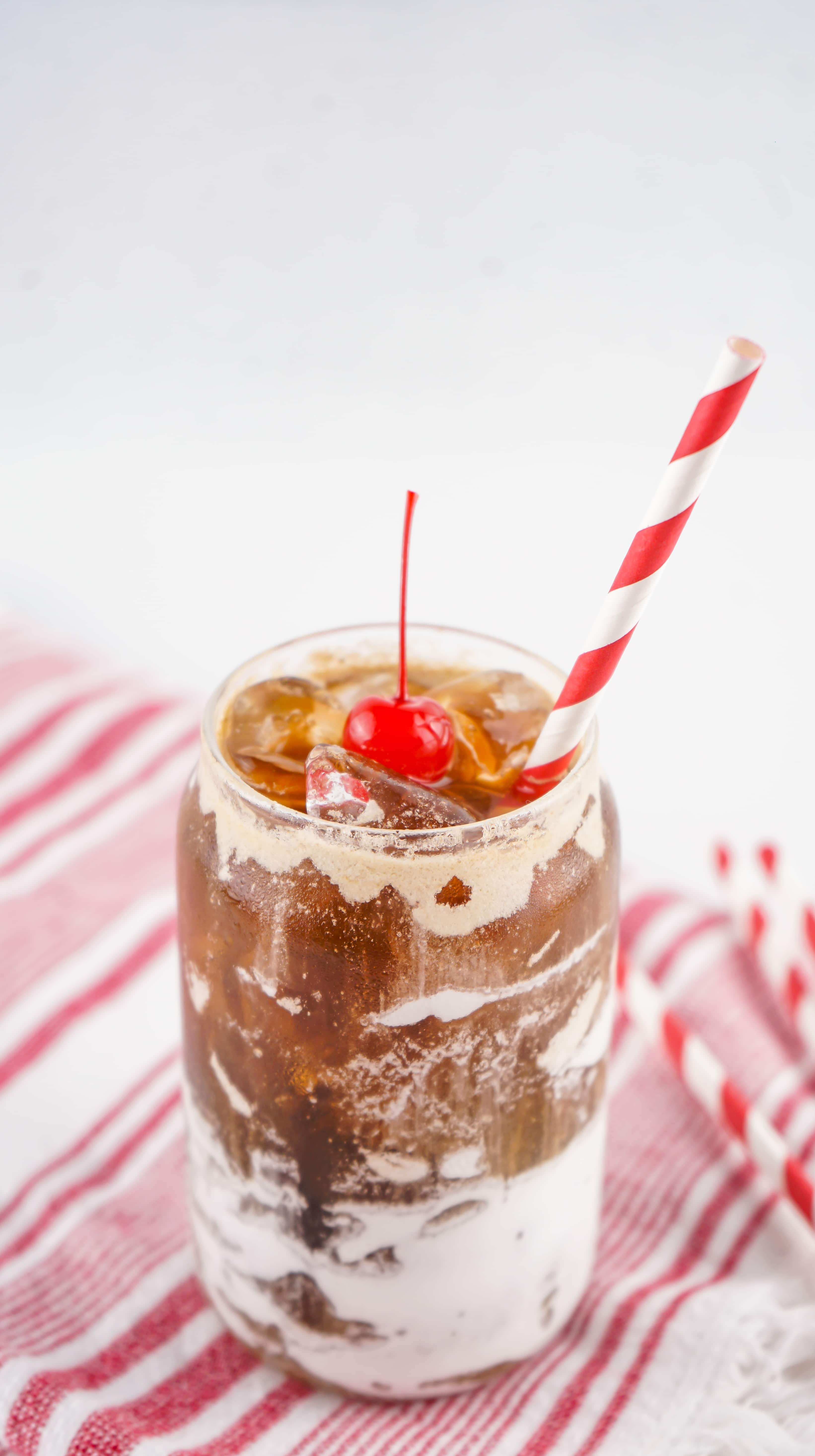 fluffy coke in a glass jar topped with a maraschino cherry