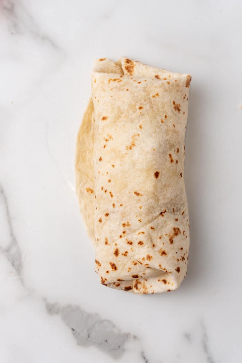 a rolled up thanksgiving leftover burrito on a marble countertop