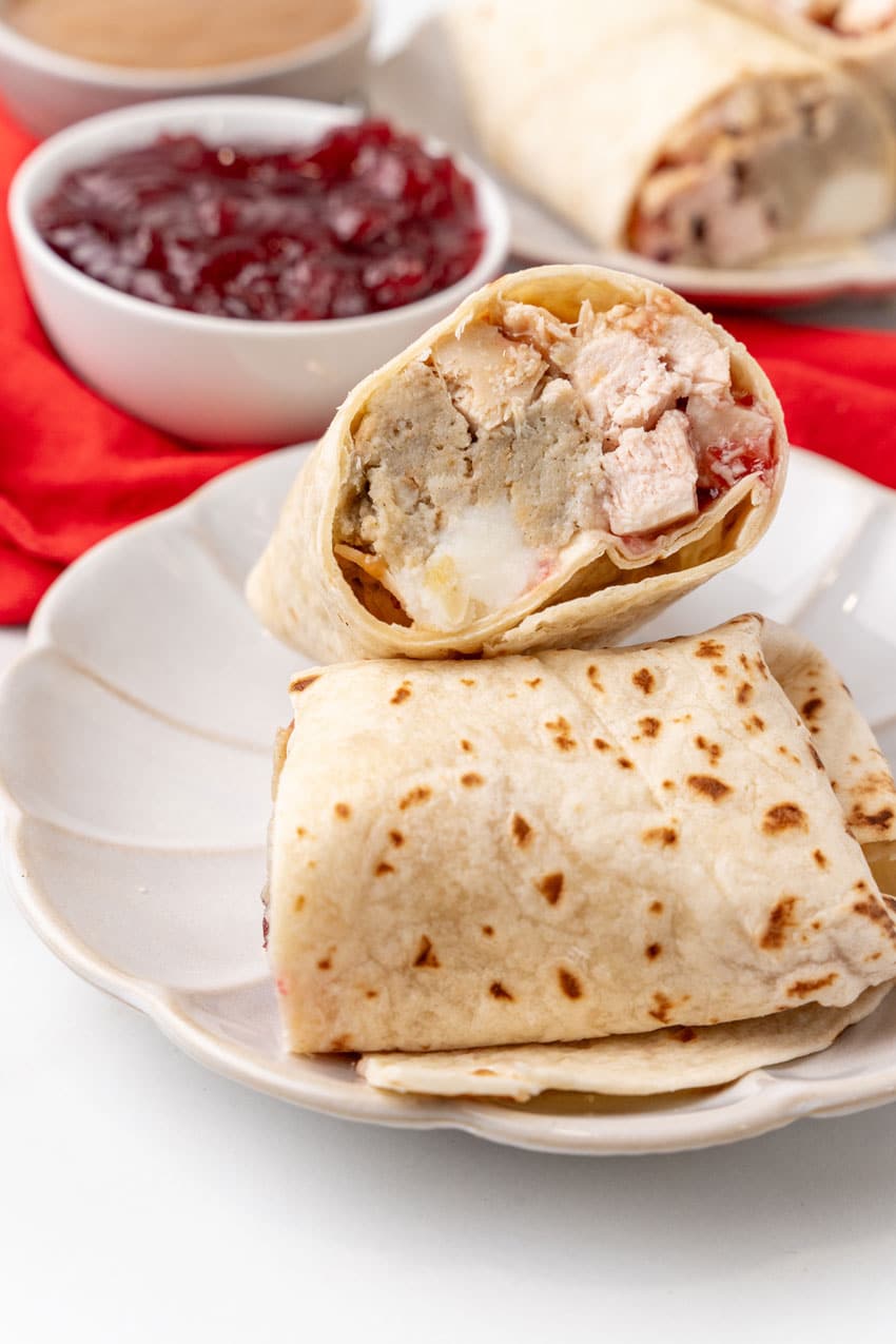 two halves of a leftover turkey burrito on a white plate