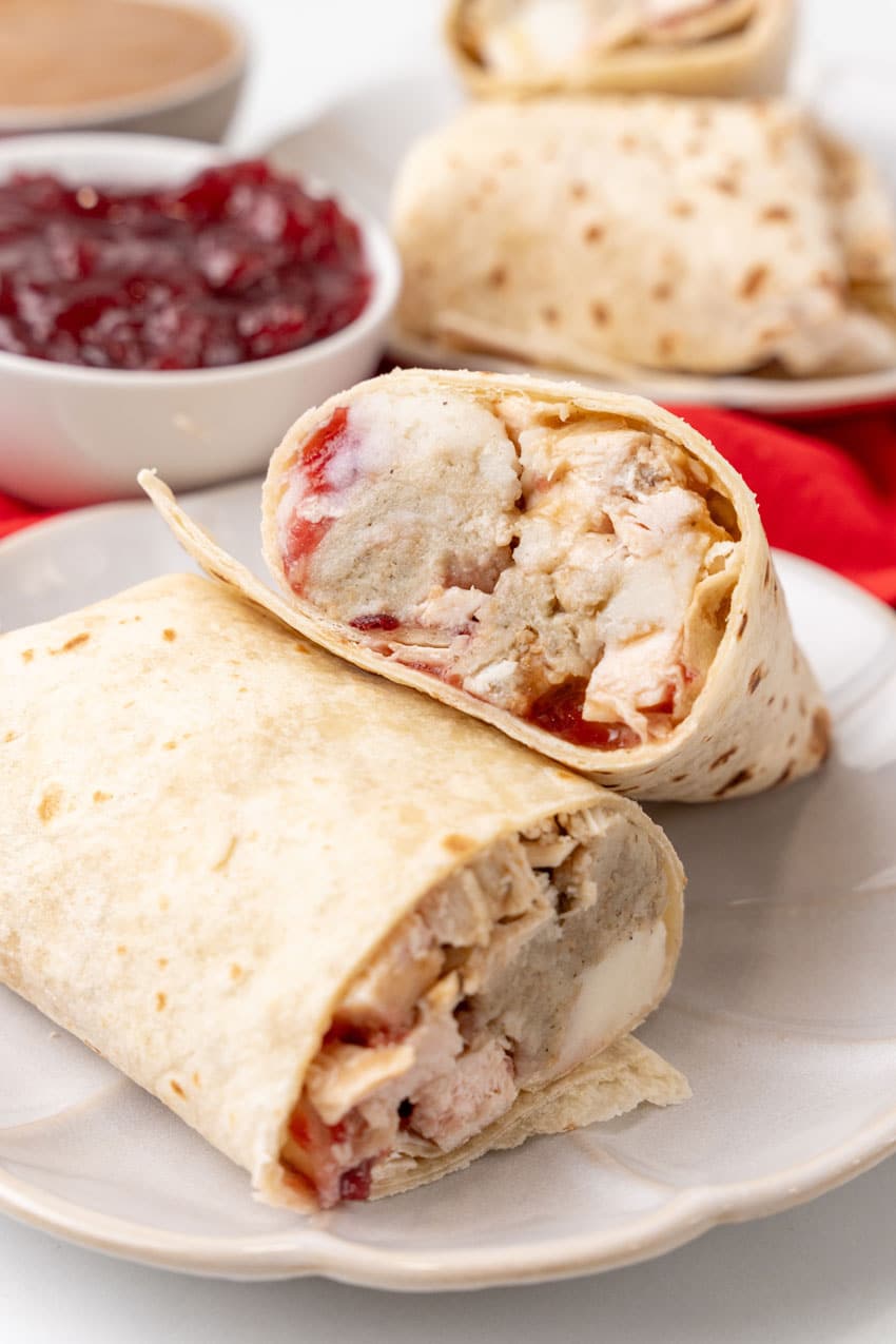 two halves of a leftover turkey burrito on a white plate