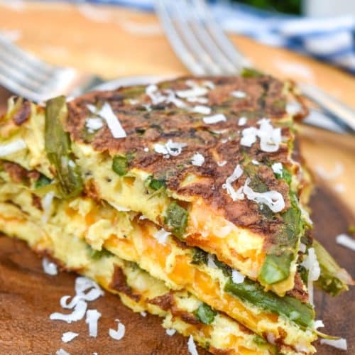 slices of cheddar asparagus frittata stacked on a wooden cutting board