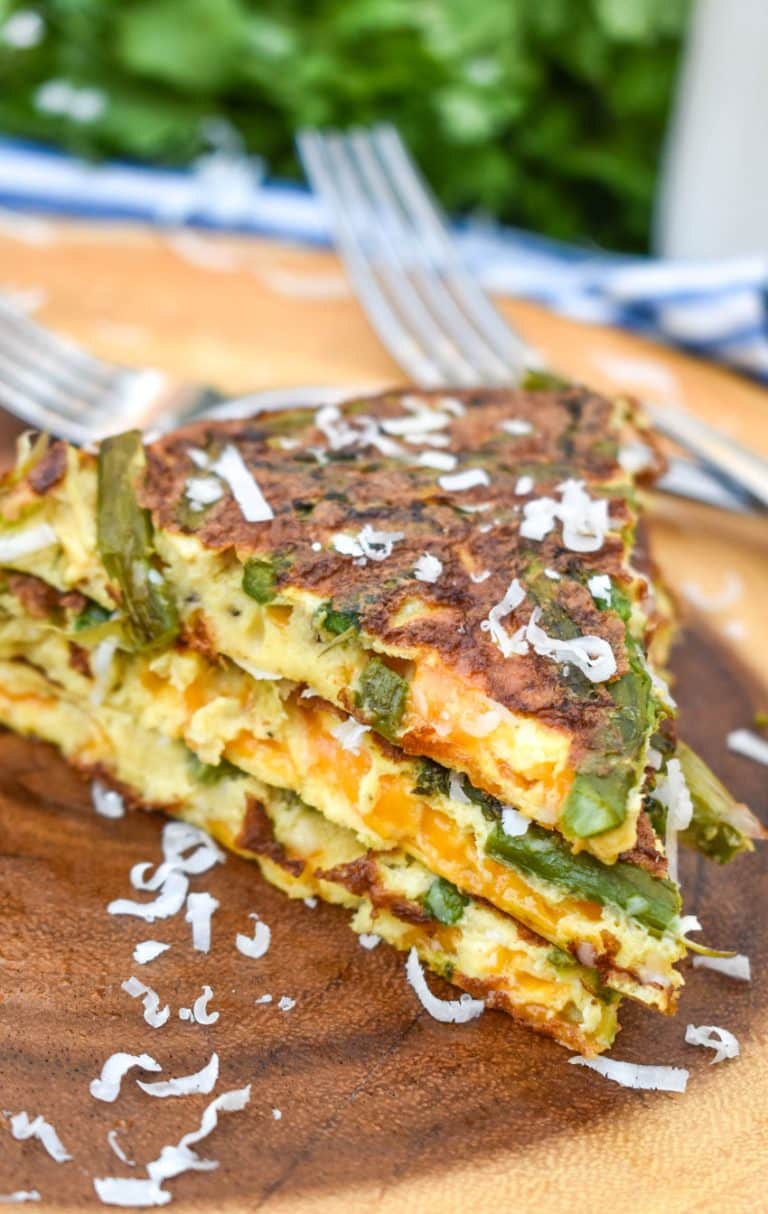 slices of cheddar asparagus frittata stacked on a wooden cutting board