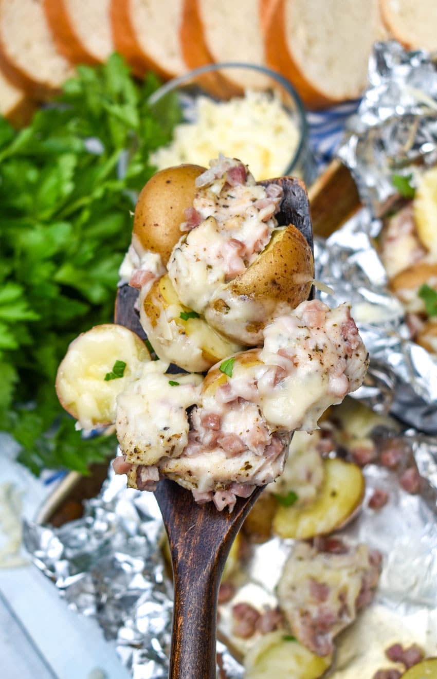 a wooden spatula holding up a scoop of cheesy chicken cordon bleu with potatoes