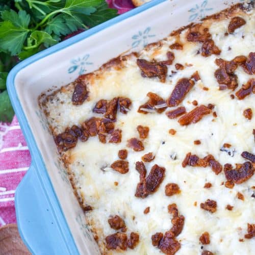 creamy caesar dip with bacon in a blue square baking dish