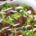 PUMPERNICKEL CROUTONS ON A GREEN SALAD IN A WHITE SERVING BOWL