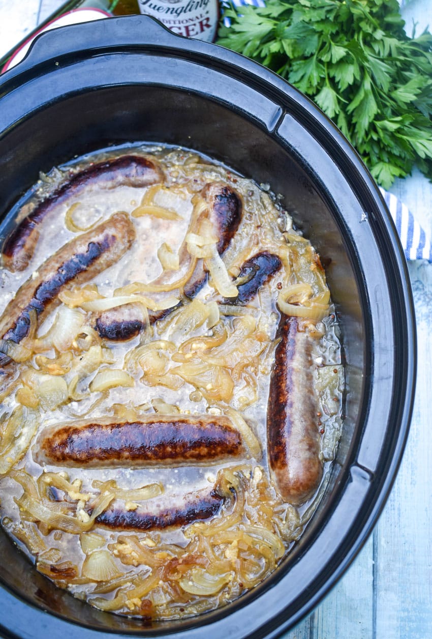 bratwurst and sauerkraut in the black crock of a slow cooker