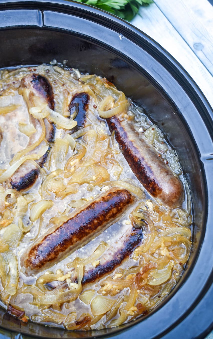 bratwurst and sauerkraut in the black crock of a slow cooker