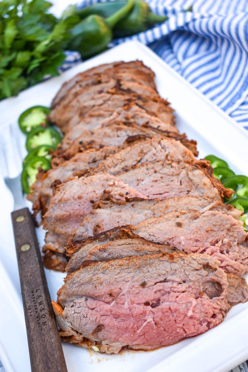 slices of smoked tri tip arranged in a row on a white serving platter