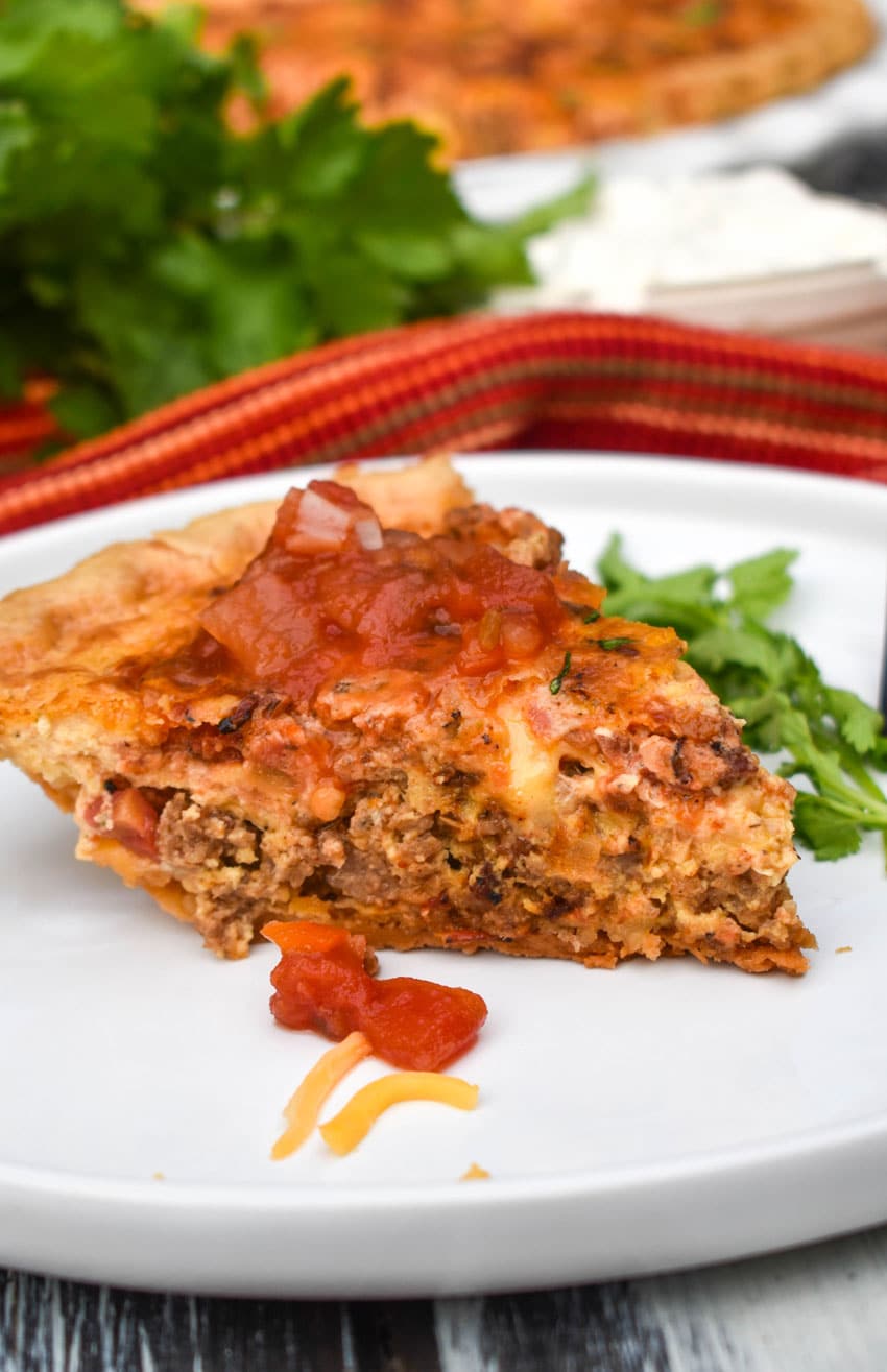 A SLICE OF A SOUTHWESTERN QUICHE TOPPED WITH SALSA ON A WHITE DINNER PLATE