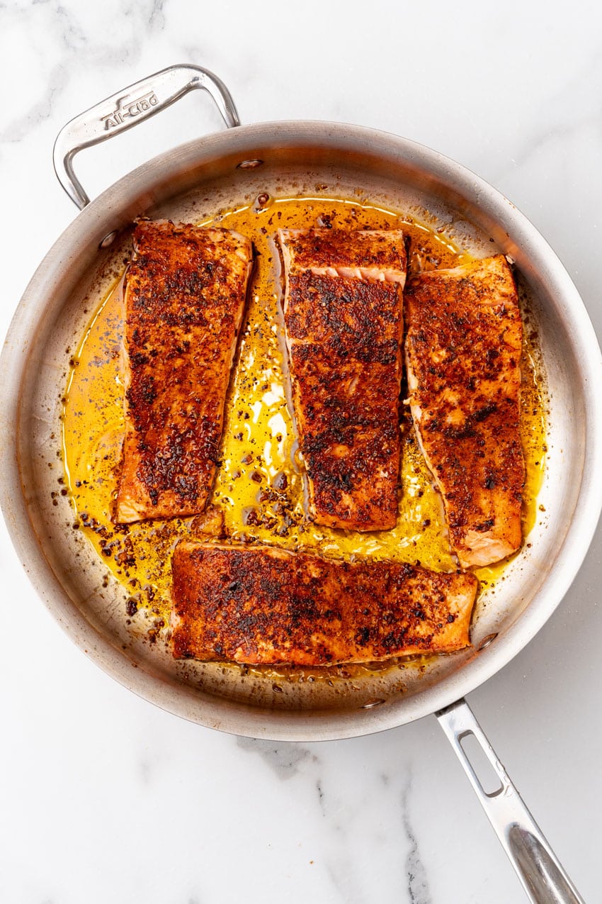 slices of seared salmon in a large metal skillet