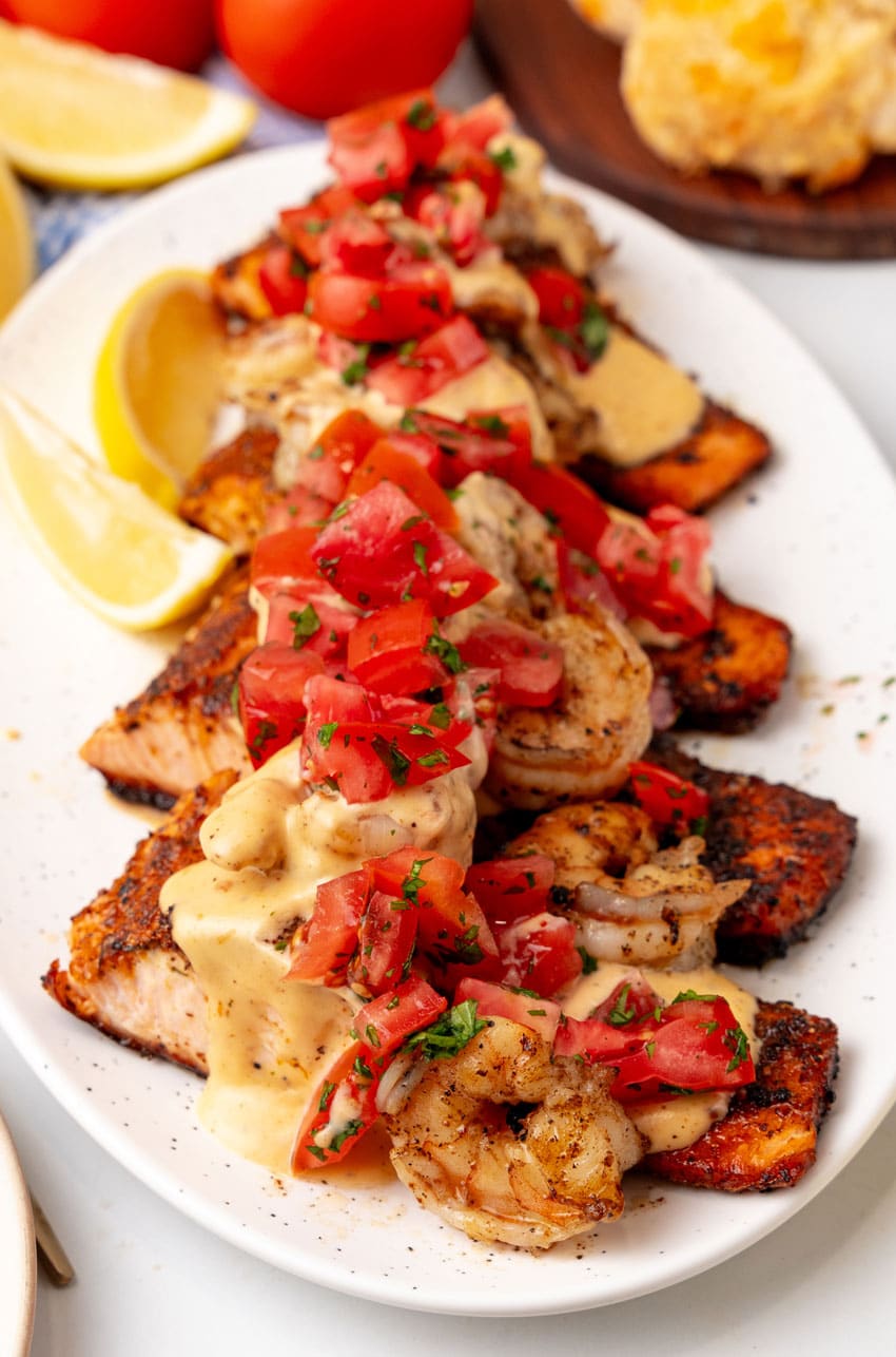 slices of salmon new orleans on a white serving platter with lemon wedges on the side