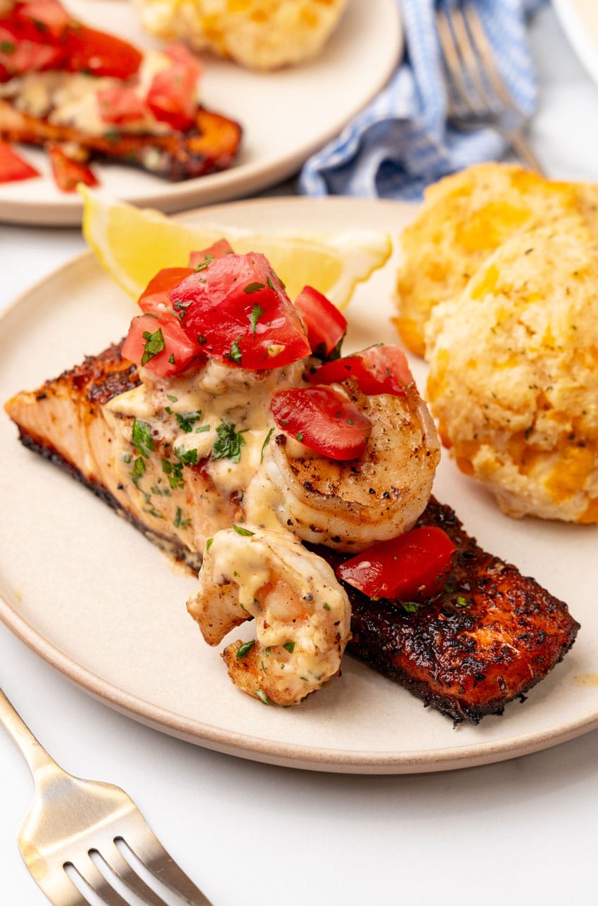 copycat red lobster salmon new orleans on a small white plate with cheddar bay biscuits on the side