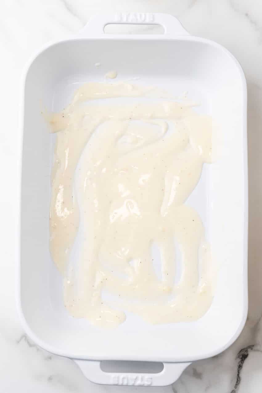 white sauce spread in the bottom of a 9x13 inch baking dish