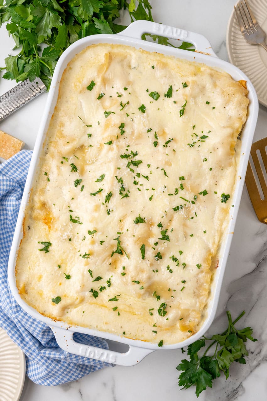 spinach artichoke lasagna in a white baking dish