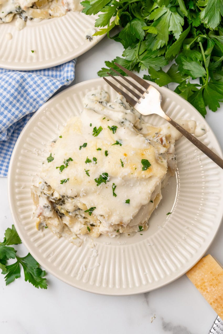 A SLICE OF SPINACH ARTICHOKE LASAGNA ON A SMALL WHITE PLATE