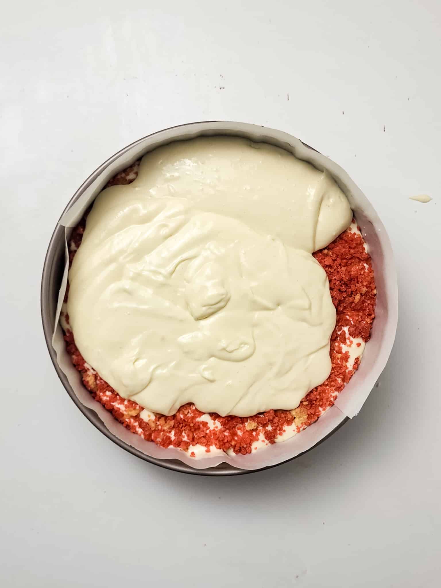 strawberry crunch topping and vanilla cheesecake batter layered in a springform pan