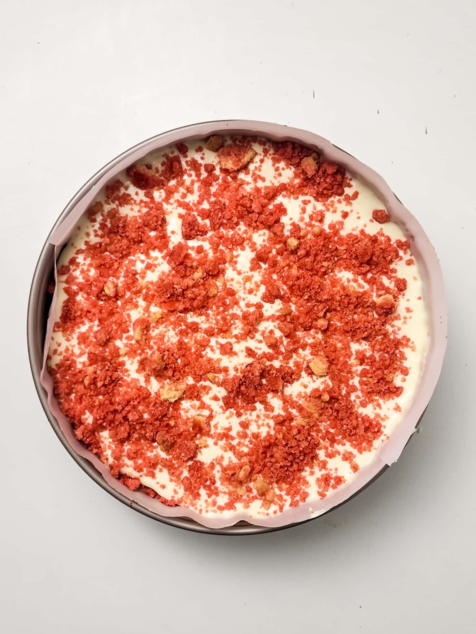 strawberry crunch topping and vanilla cheesecake batter layered in a springform pan