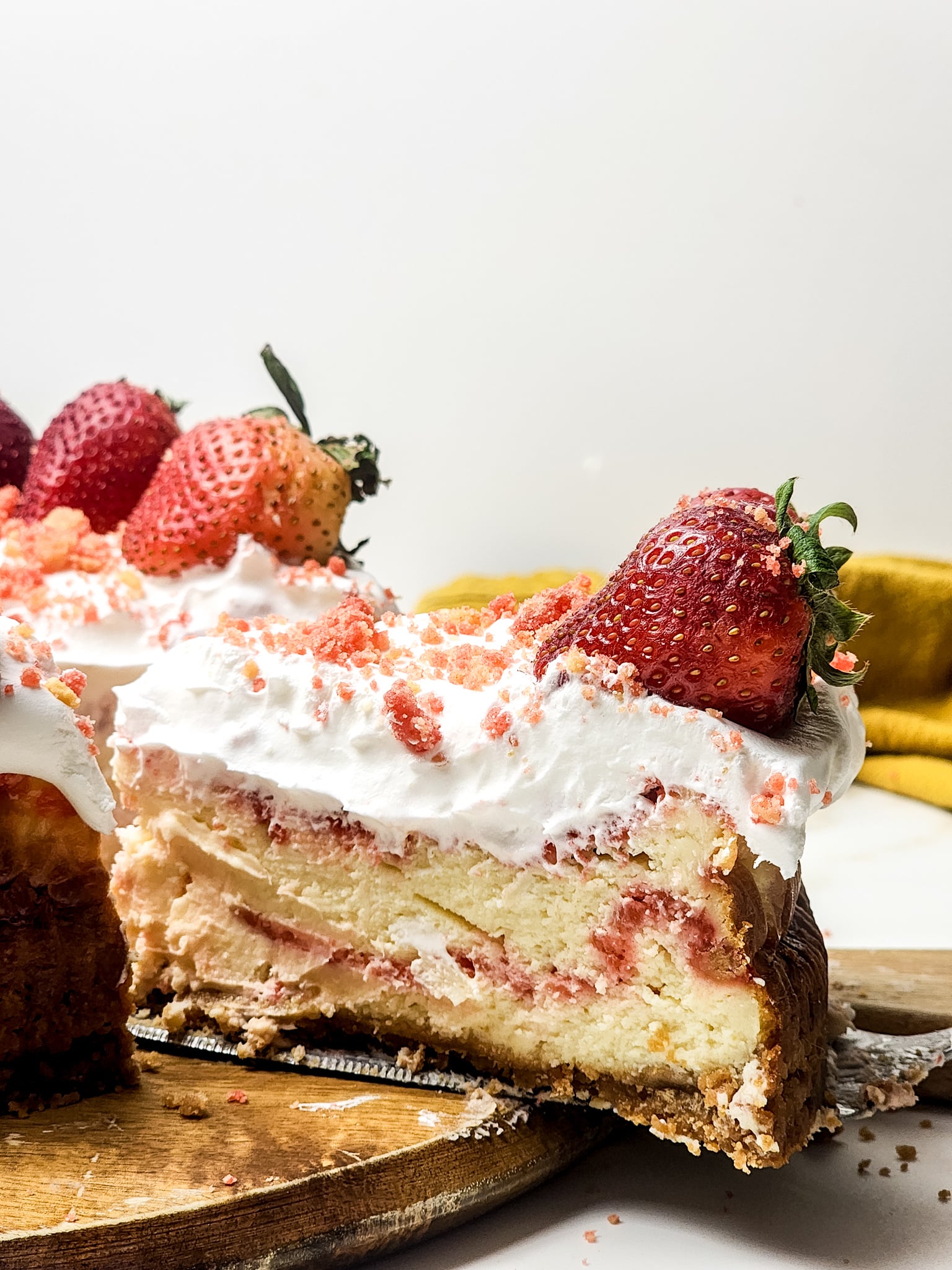 a cake server holding up a slice of homemade strawberry crunch cheesecake