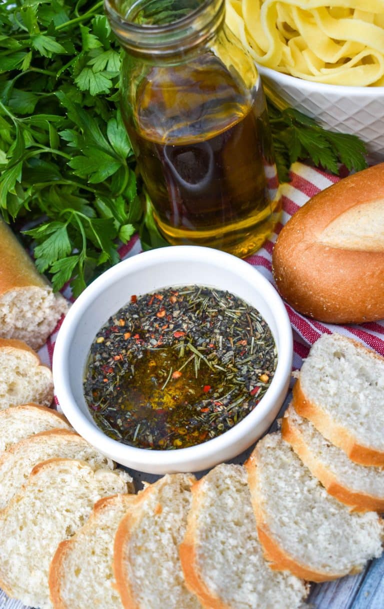 copycat carrabba's bread dipping oil in a small white bowl surrounded by slices of baguette bread