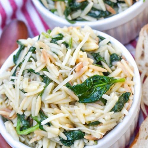 spinach parmesan orzo topped with shredded parmesan cheese in two small white ramekins