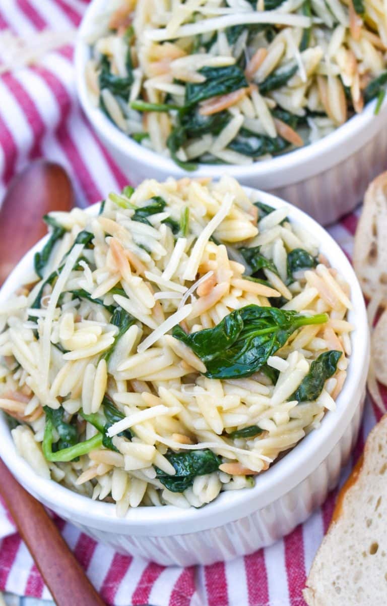 spinach parmesan orzo topped with shredded parmesan cheese in two small white ramekins