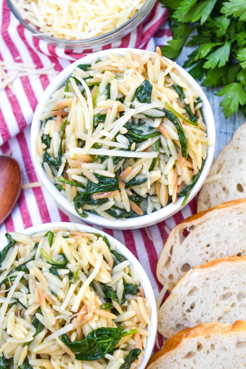 spinach parmesan orzo topped with shredded parmesan cheese in two small white ramekins