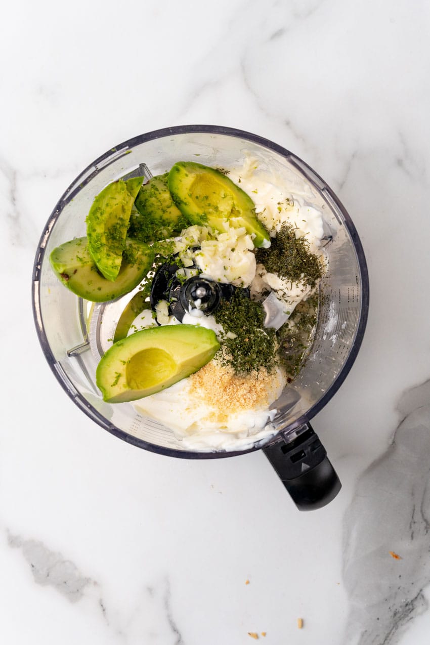 avocado lime dressing ingredients in the bowl of a food processor fitted with the blade attachment