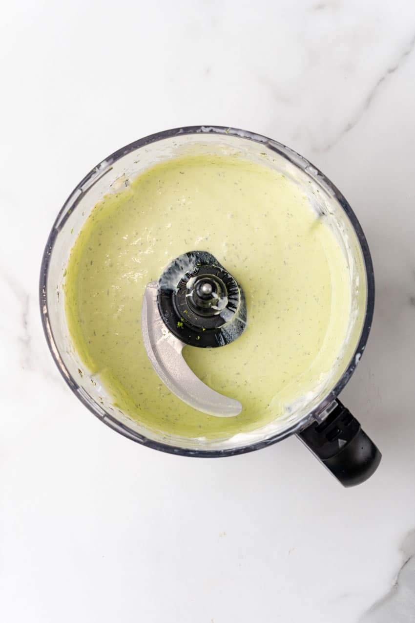 homemade avocado lime dressing in the bowl of a food processor fitted with the blade attachment