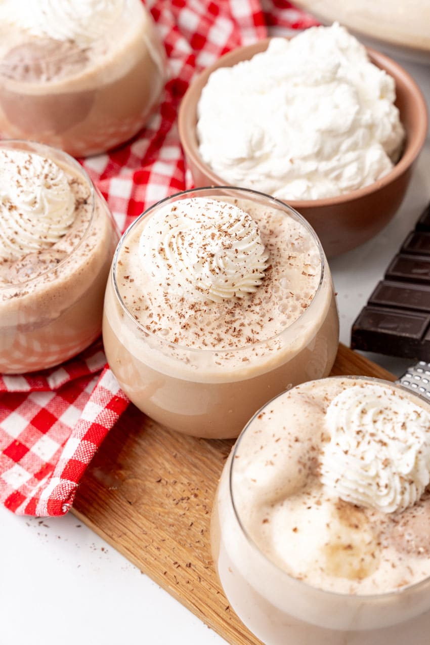 southern coffee punch in glasses topped with piped whipped cream swirls and shaved chocolate on a wooden cutting board