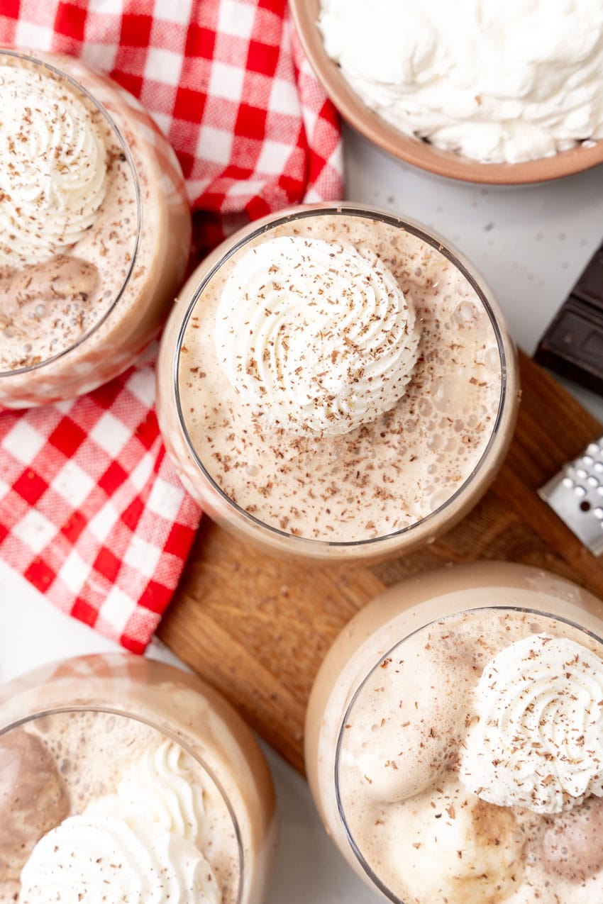 southern coffee punch in glasses topped with piped whipped cream swirls and shaved chocolate on a wooden cutting board 