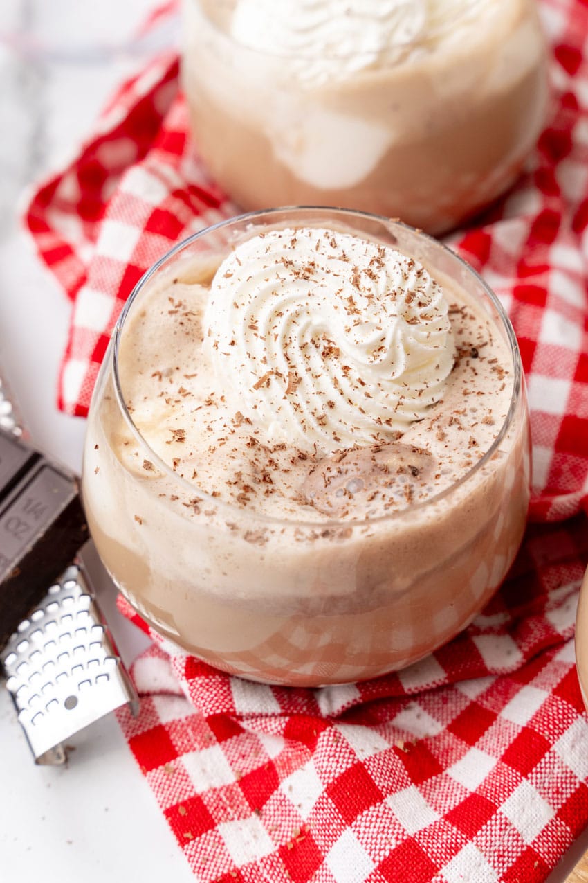 southern coffee punch in glasses topped with piped whipped cream swirls and shaved chocolate on a wooden cutting board 