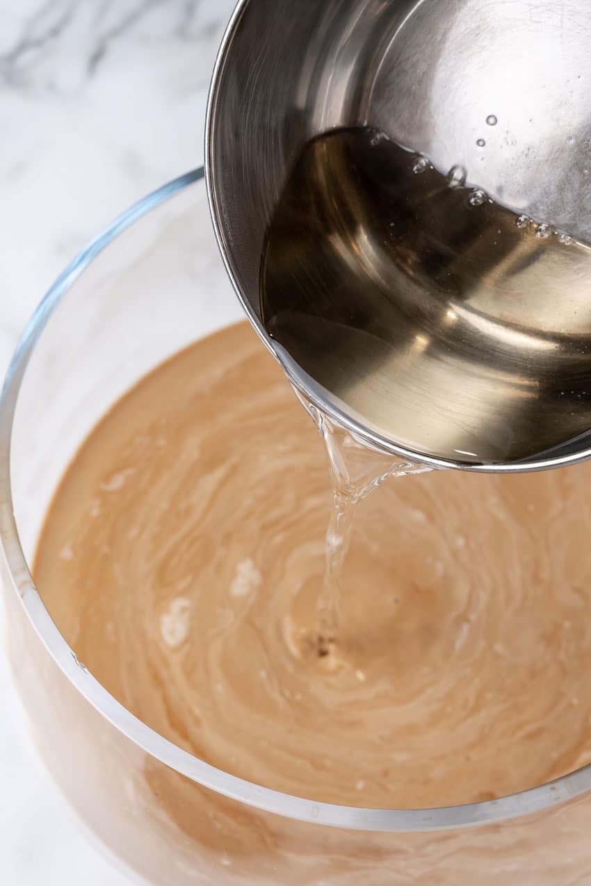 simple syrup being poured into a glass punch bowl filled with creamed coffee