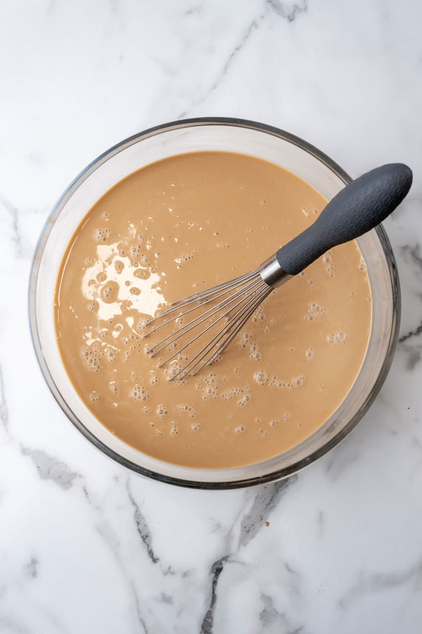 creamed coffee mixed with simple syrup in a glass mixing bowl