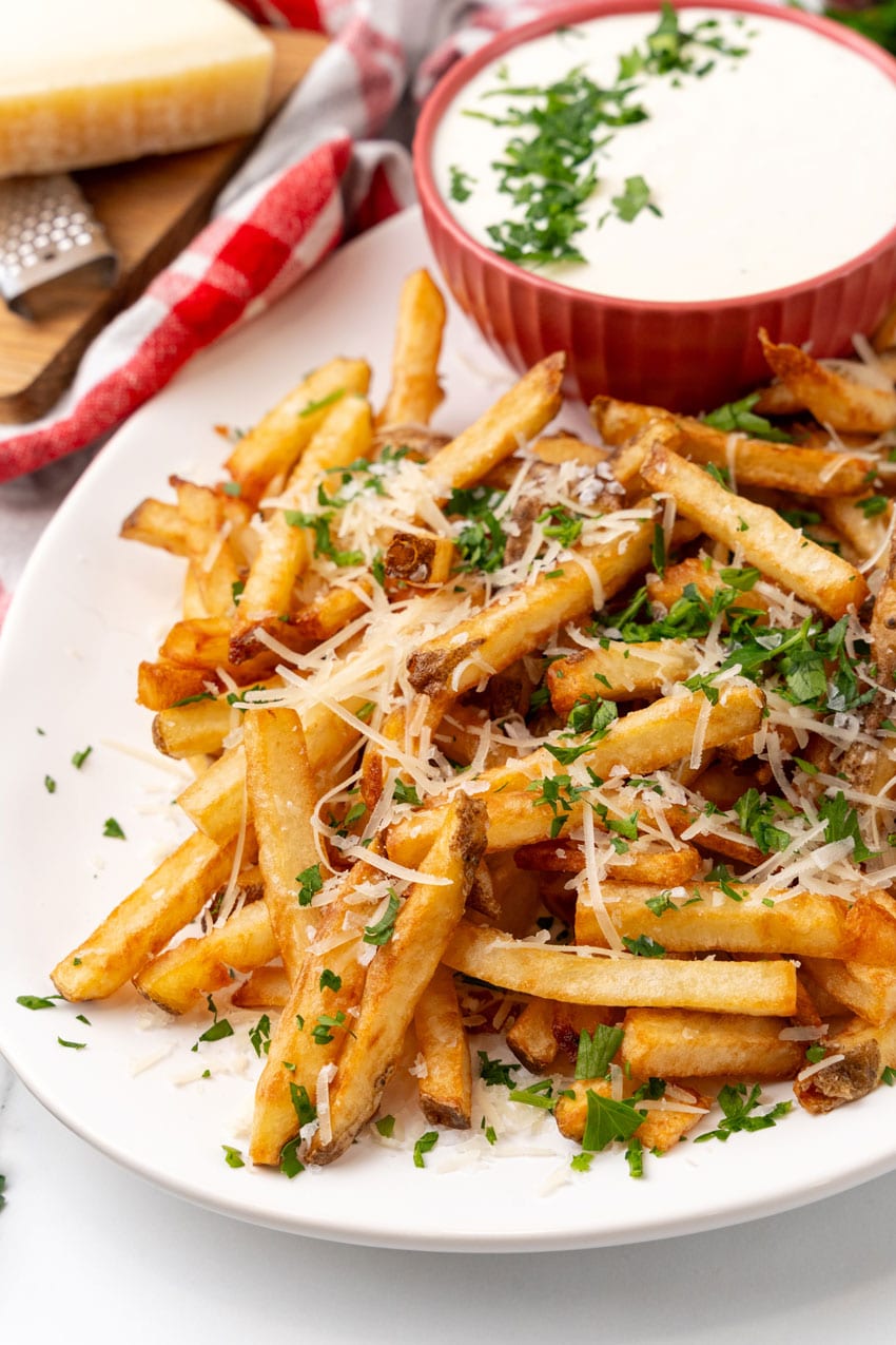 a close up of Parmesan truffle fries with garlic aioli on a white serving platter