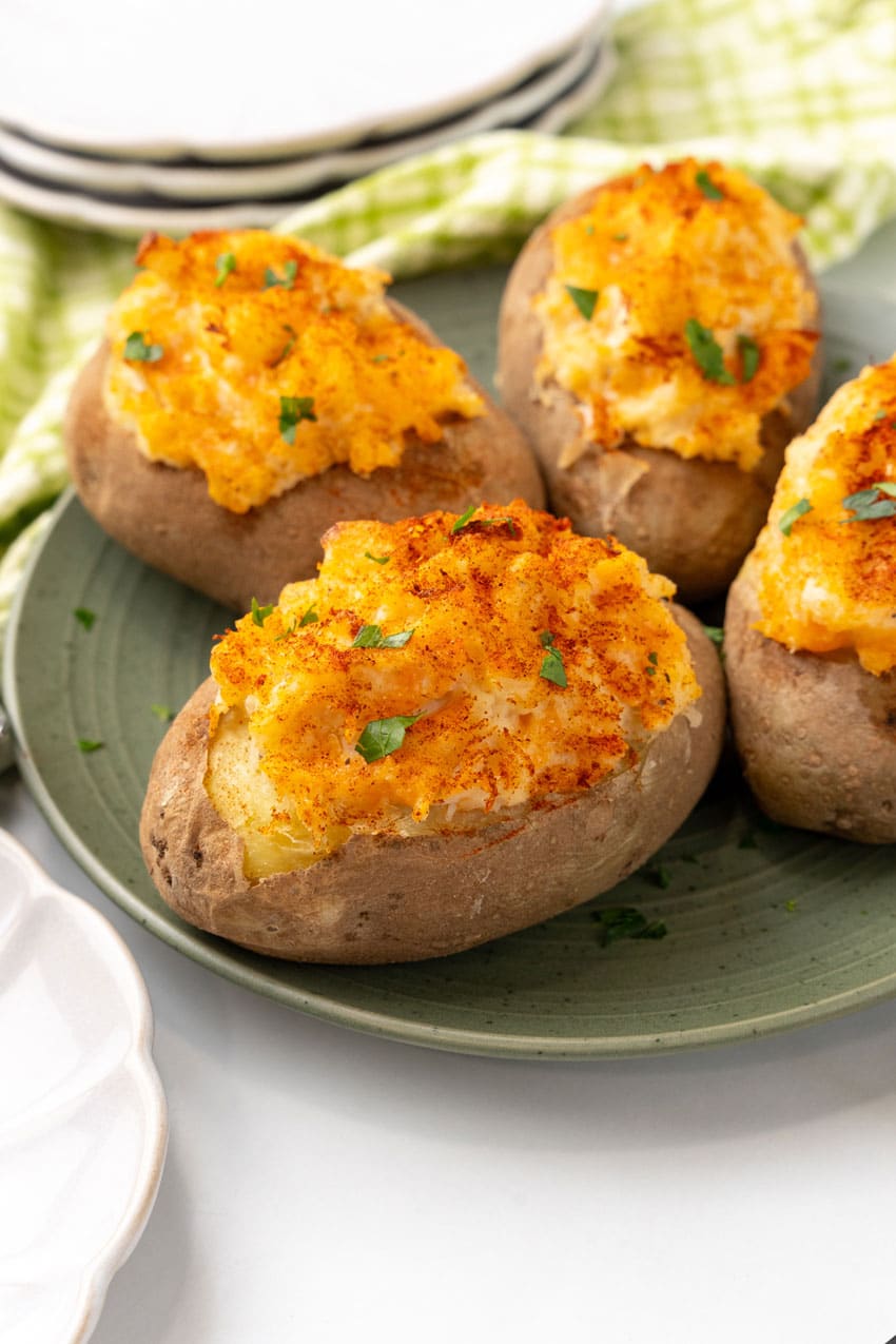 four twice baked crab stuffed potatoes on a green plate