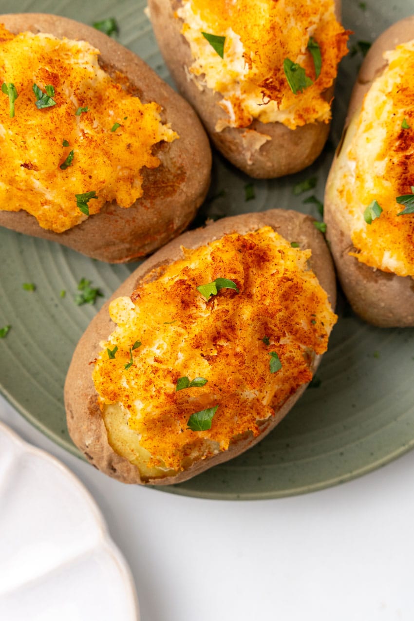 four twice baked crab stuffed potatoes on a green plate